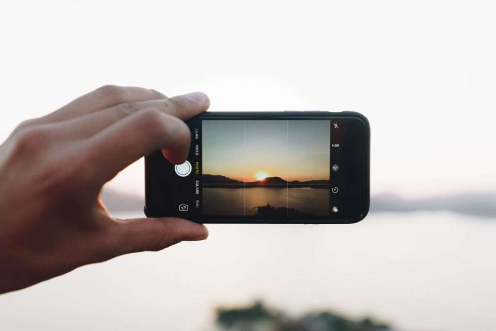 Somone holding an iphone and taking a landscape photo